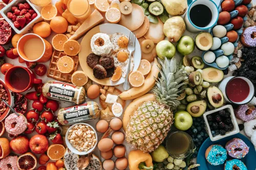 Ein reichhaltig gedeckter Tisch mit Obst, Käse, Saucen und Süßigkeiten in verschiedensten Farbtönen